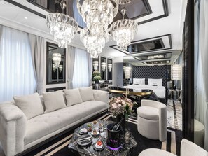 Un salon luxueux avec un canapé moelleux, une table basse sur laquelle repose une bouteille de champagne et un lustre.