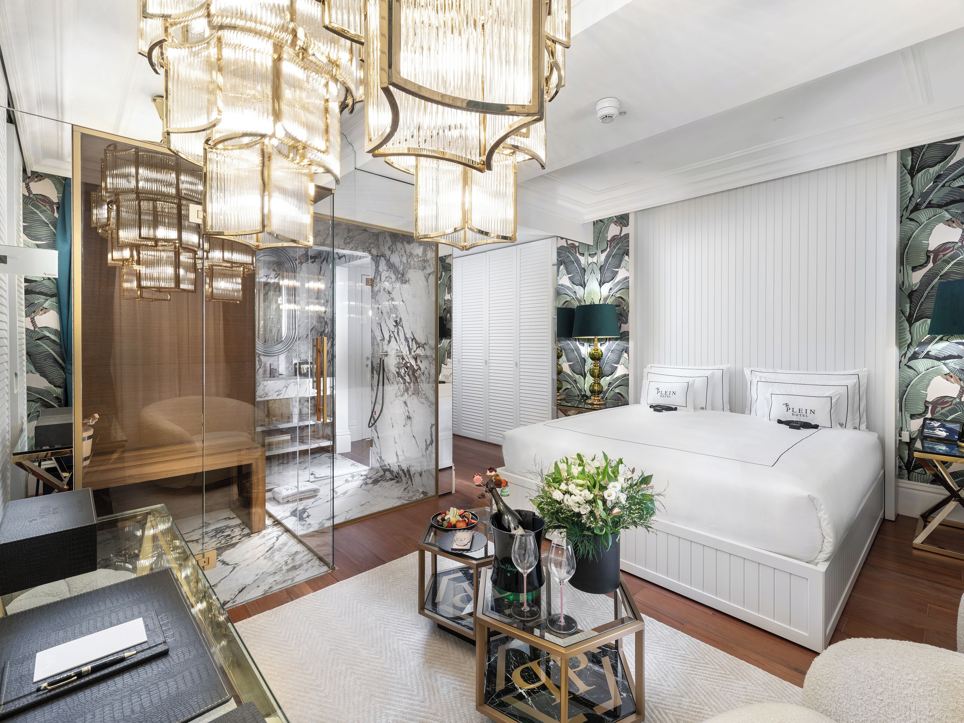 Une chambre moderne avec un grand lit, une douche en verre et un lustre.