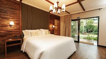 Habitación de hotel con una cama grande, una araña de cristal, una pared de madera y un ventanal corredero al exterior.