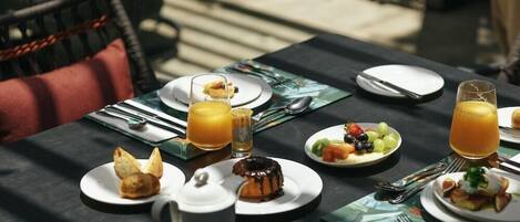 A breakfast setting with plates of food, a coffee pot, and glasses of orange juice.