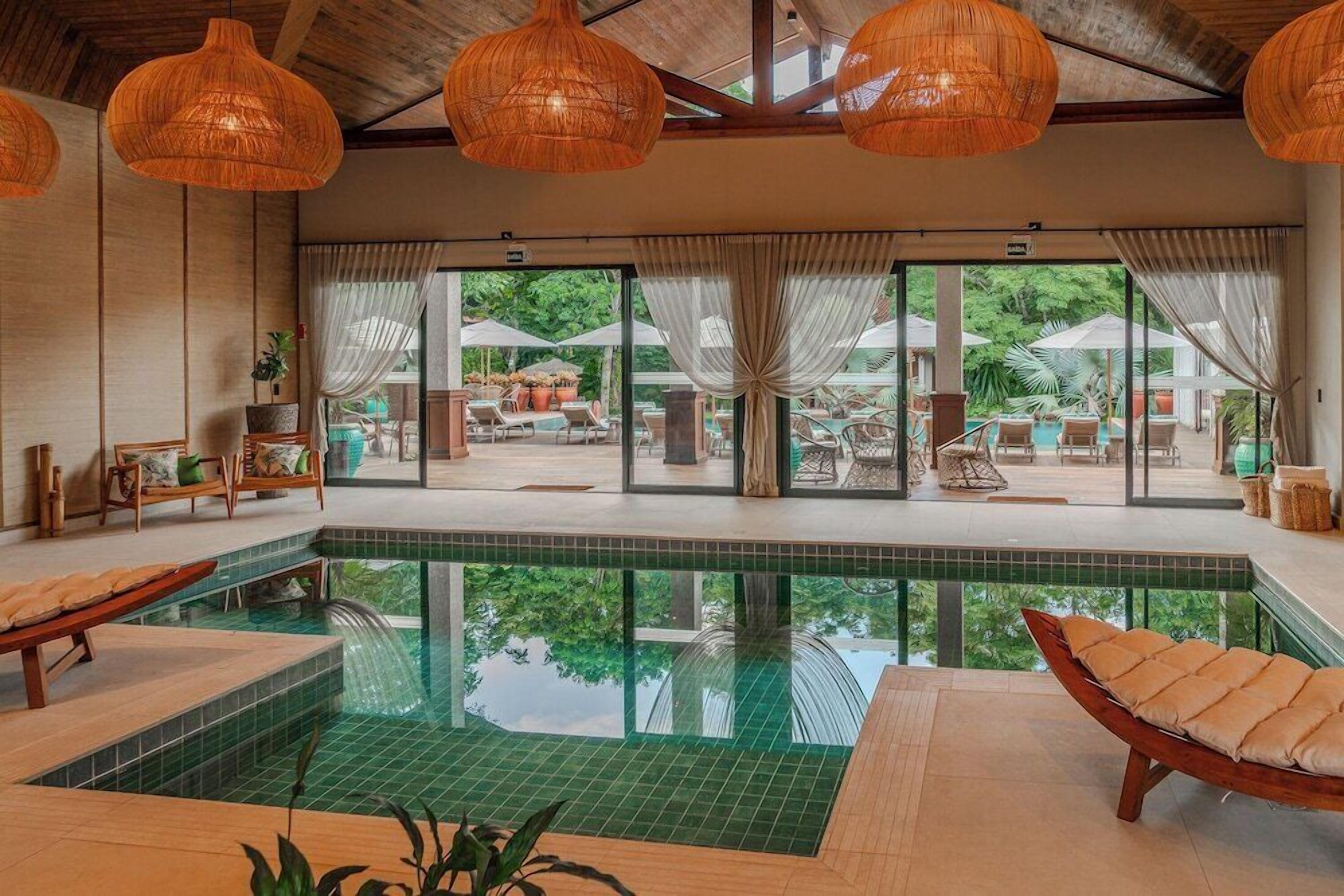 Área da piscina com espreguiçadeiras, uma piscina pequena e vista para o pátio externo.