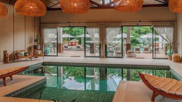 Área da piscina com espreguiçadeiras, uma piscina pequena e vista para o pátio externo.