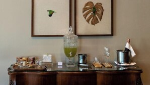 A wall with four framed pictures, a wooden console table with various items, and a green drink on the table. - Las Hotel Boutique (Foz do Iguaçu)