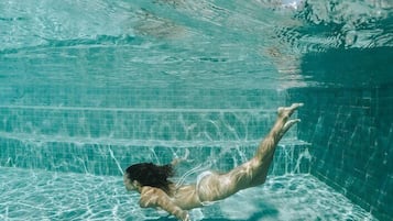 Vista subacuática de una piscina con agua cristalina y una persona nadando.