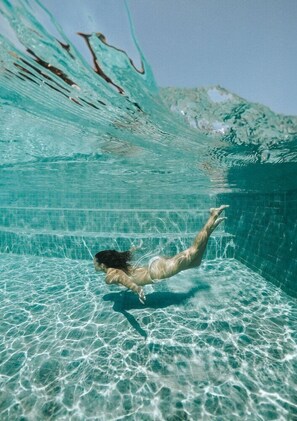 Vista subacuática de una piscina con agua cristalina y una persona nadando.