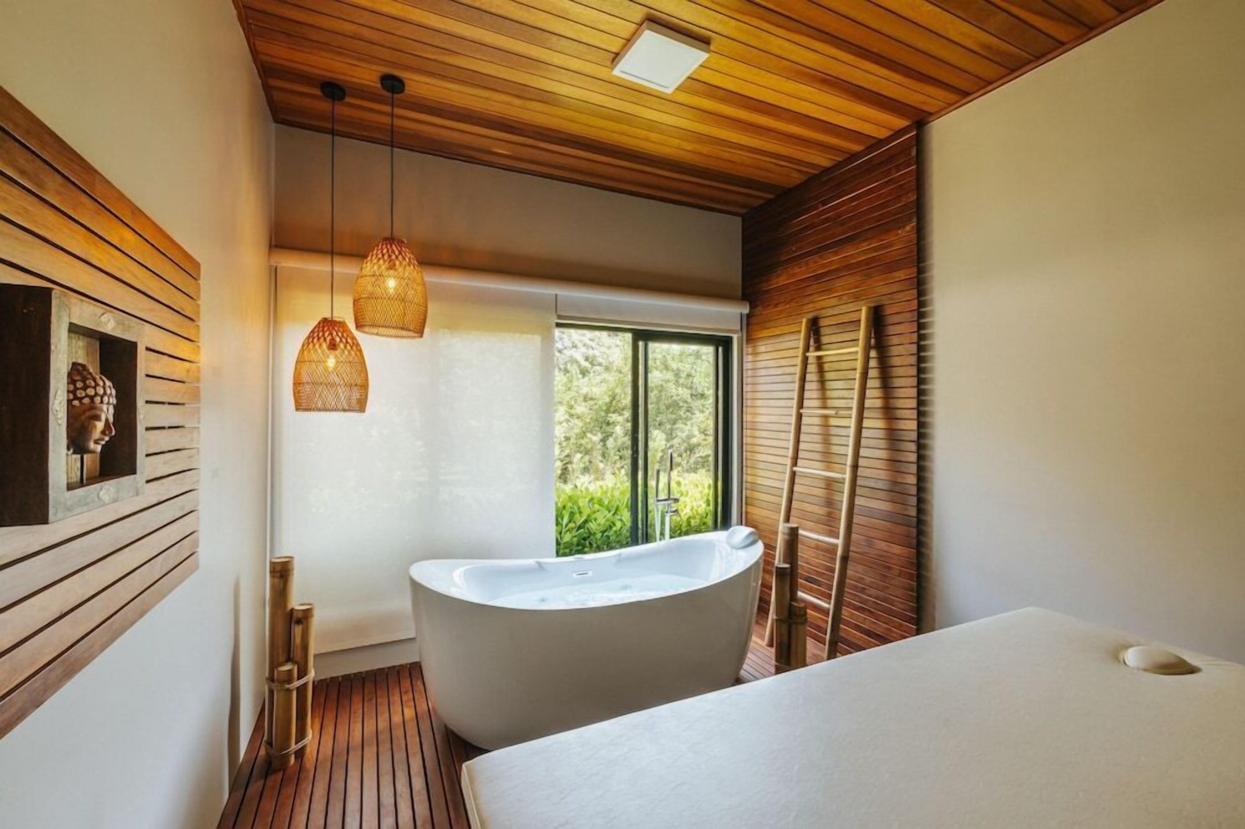 Ein modernes Badezimmer mit freistehender Badewanne, Holztäfelung an den Wänden und einem großen Fenster, das für natürliches Licht sorgt.