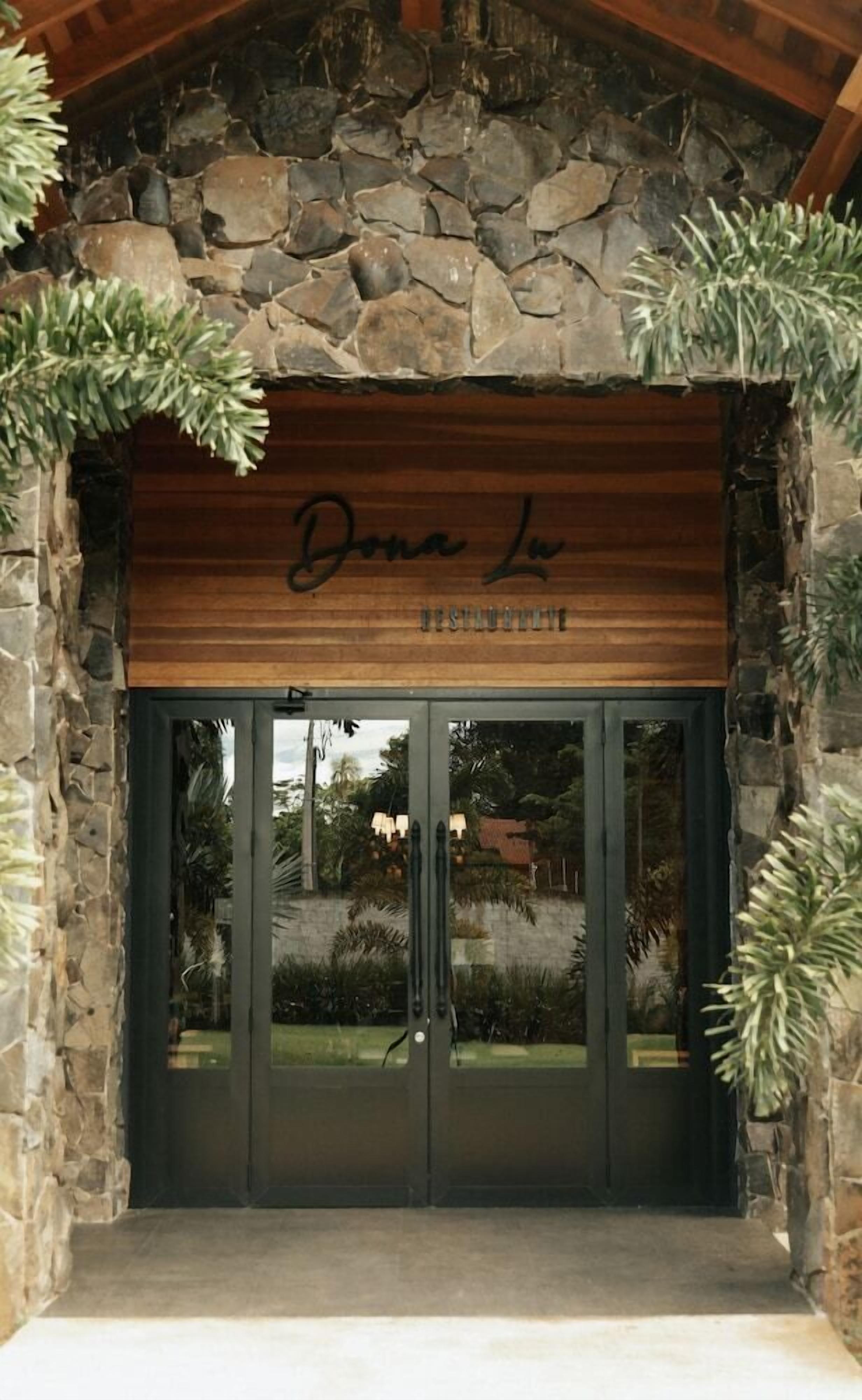 Una entrada enmarcada en piedra con un letrero de madera que dice 'Dona Le Boutique'.