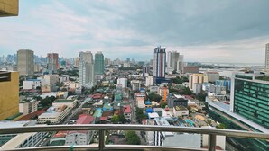 A cityscape with a mix of high-rise and low-rise buildings, a clear sky, and a distant view of the sea. - Birchtower by Jeizel Manila City By Zuzu (Manila)