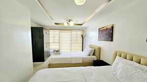 A hotel room with two beds, a window with blinds, a painting on the wall, and a ceiling light fixture. - Birchtower by Jeizel Manila City By Zuzu (Manila)