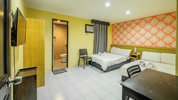 A hotel room with a bed, a desk, a chair, a TV, and a bathroom visible through an open door. - Hotel Juliano By Zuzu (Manila)