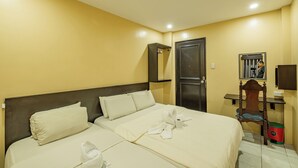 A hotel room with two beds, a wooden headboard, a small table, a mirror, and a door. - Hotel Juliano By Zuzu (Manila)
