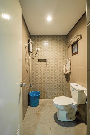 A bathroom with a toilet, a shower, and a blue bucket. - Hotel Juliano By Zuzu (Manila)