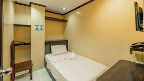 A hotel room with a single bed, a wooden chair, a small table, a TV mounted on the wall, and a sign indicating the room's features. - Hotel Juliano By Zuzu (Manila)