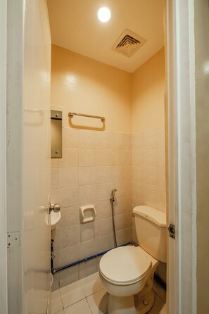 A small, compact bathroom with a toilet, sink, and shower. - Hotel Juliano By Zuzu (Manila)