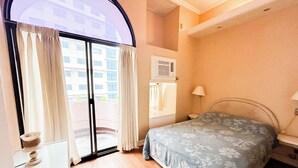 Une chambre à coucher avec un lit, une fenêtre avec des rideaux, un radiateur et une porte donnant sur un espace extérieur.