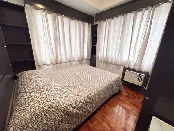 Un dormitorio con una colcha estampada, un armario empotrado y un radiador.