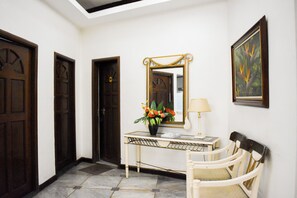 A hallway with a console table, a mirror, a lamp, and a chair. - Sunette Tower Suites Makati City Center By Zuzu (Makati)