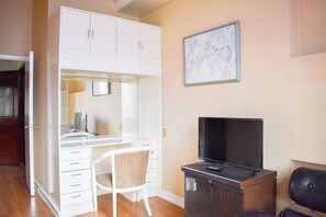A bedroom with a white wardrobe, a desk with a chair, a television, and a framed picture on the wall. - Sunette Tower Suites Makati City Center By Zuzu (Makati)