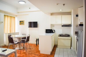 Cocina compacta equipada con microondas, tostadora y refrigerador.  Comedor con mesa y sillas.
