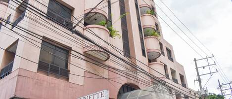A multi-story building with balconies, a sign for 'Sunette Tower Condo Suites', and various signs including 'HANADY 2'.