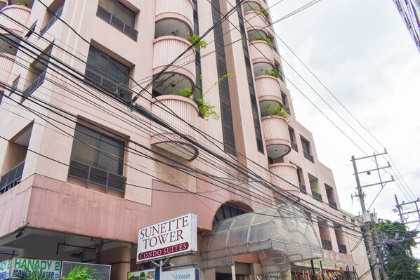 A multi-story building with balconies, a sign for 'Sunette Tower Condo Suites', and various signs including 'HANADY 2'. - Sunette Tower Suites Makati City Center By Zuzu (Makati)