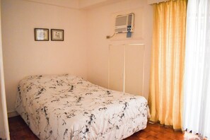A bedroom with a bed, an air conditioner, and a door. - Sunette Tower Suites Makati City Center By Zuzu (Makati)
