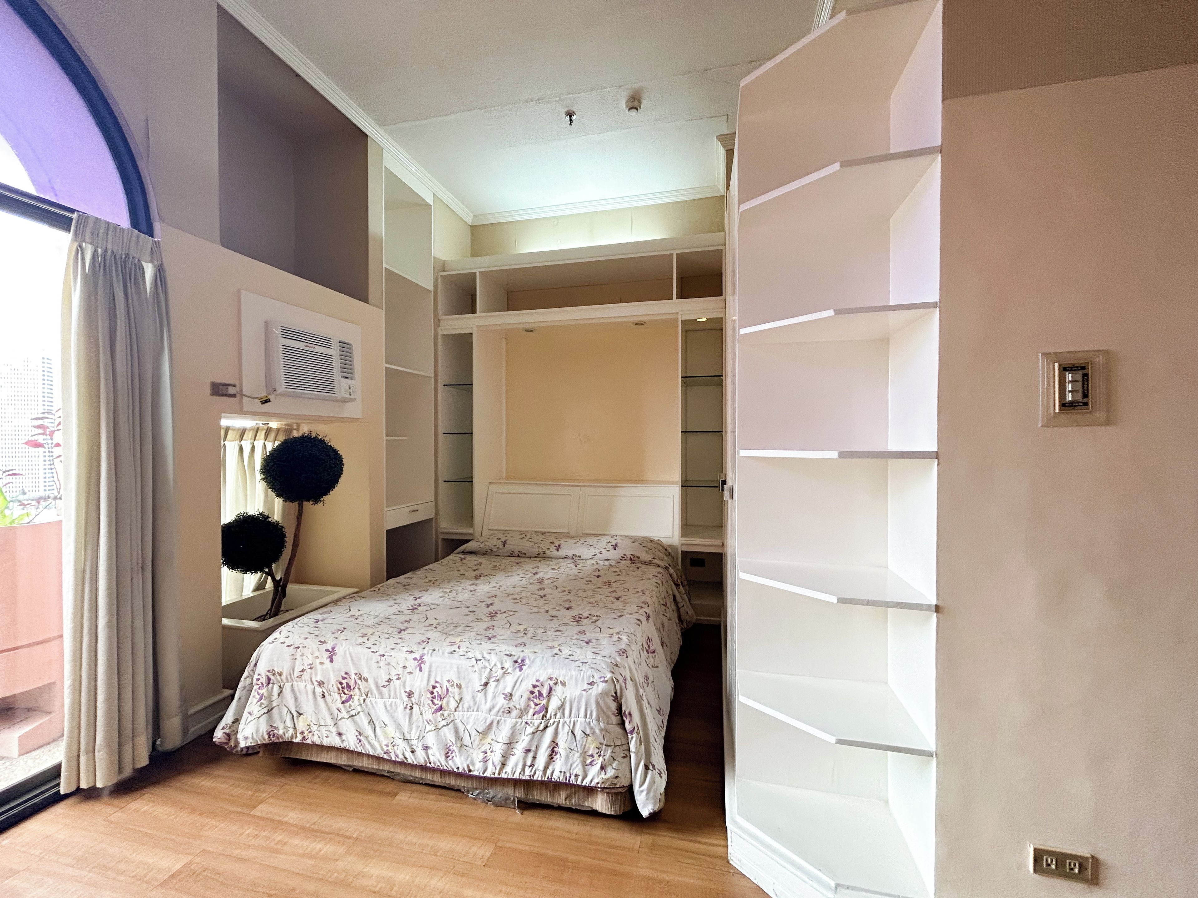 Ein Schlafzimmer mit Bett, Kleiderschrank und einem Fenster mit Vorhängen.