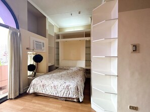 Een slaapkamer met een bed, een garderobe en een raam met gordijnen.