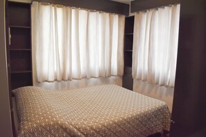 A bedroom with a bed, two windows with curtains, and a built-in wardrobe. - Sunette Tower Suites Makati City Center By Zuzu (Makati)