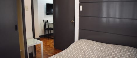 A bedroom with a bed, a desk, and a chair.
