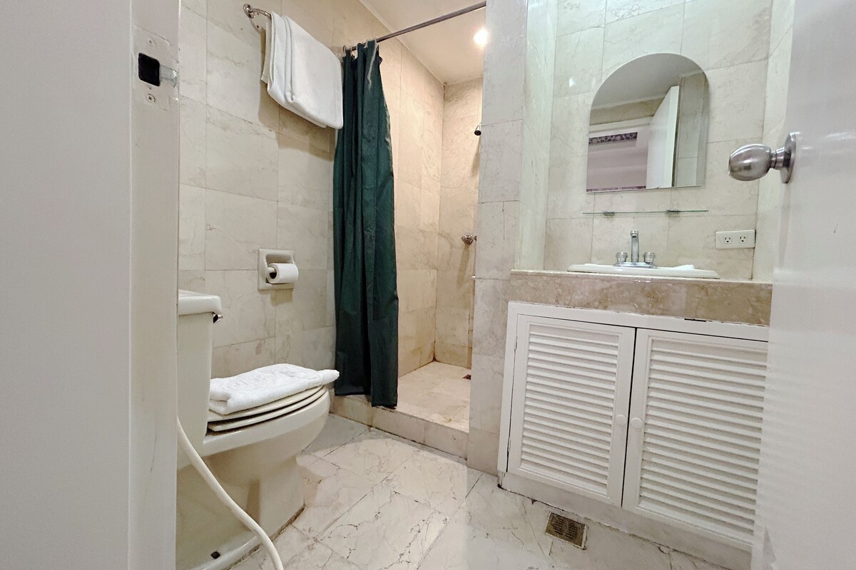A bathroom with a toilet, shower, and sink.