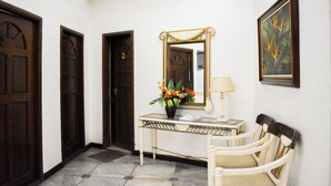 Un couloir avec une console, un miroir, une lampe et une chaise.