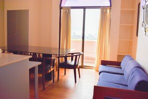 A room with a dining table, chairs, a sofa, and a sliding glass door leading to an outdoor balcony. - Sunette Tower Suites Makati City Center By Zuzu (Makati)