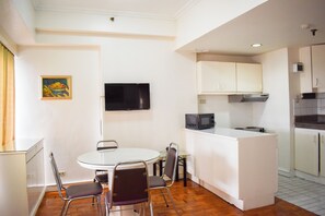 A compact kitchen with a dining area, a microwave, and a flat-screen TV. - Sunette Tower Suites Makati City Center By Zuzu (Makati)