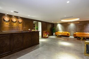 A hotel lobby with a reception desk, a sofa, and a potted plant. - Palazzo 3 (Da Nang Municipality)