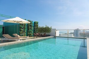 A rooftop infinity pool with lounge chairs and a table, surrounded by greenery and a clear view of the city skyline. - Palazzo 3 (Da Nang Municipality)