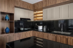 A modern kitchen with wooden cabinetry, black countertops, and built-in appliances. - Palazzo 3 Hotel (Da Nang Municipality)
