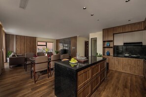 A modern kitchen with a central island, wooden cabinetry, and a dining area with a table and chairs. - Palazzo 3 Hotel (Da Nang Municipality)