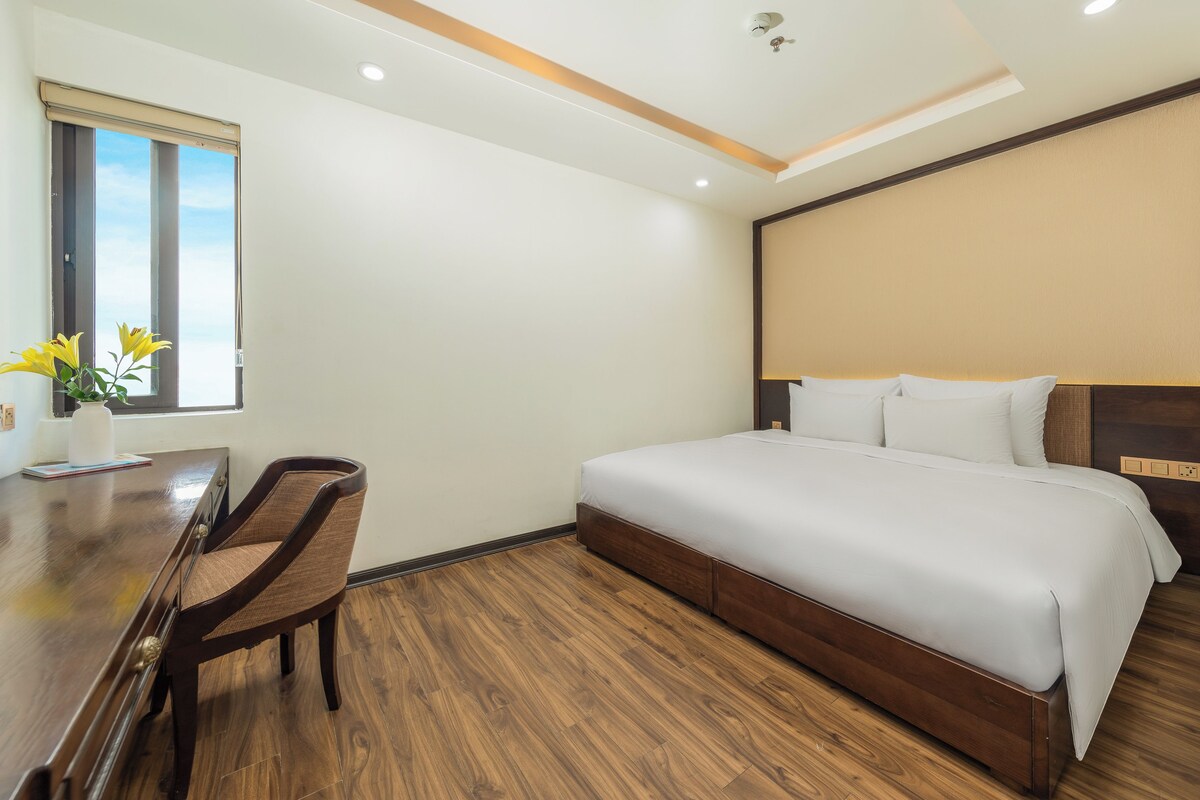A hotel room with a bed, a desk, and a chair.
