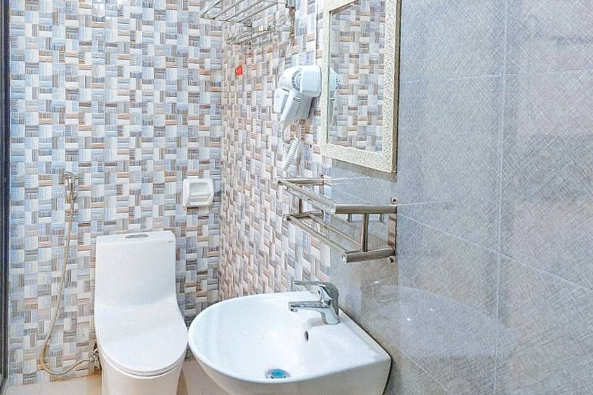 A bathroom with a tiled wall, a toilet, a sink, and a mirror.