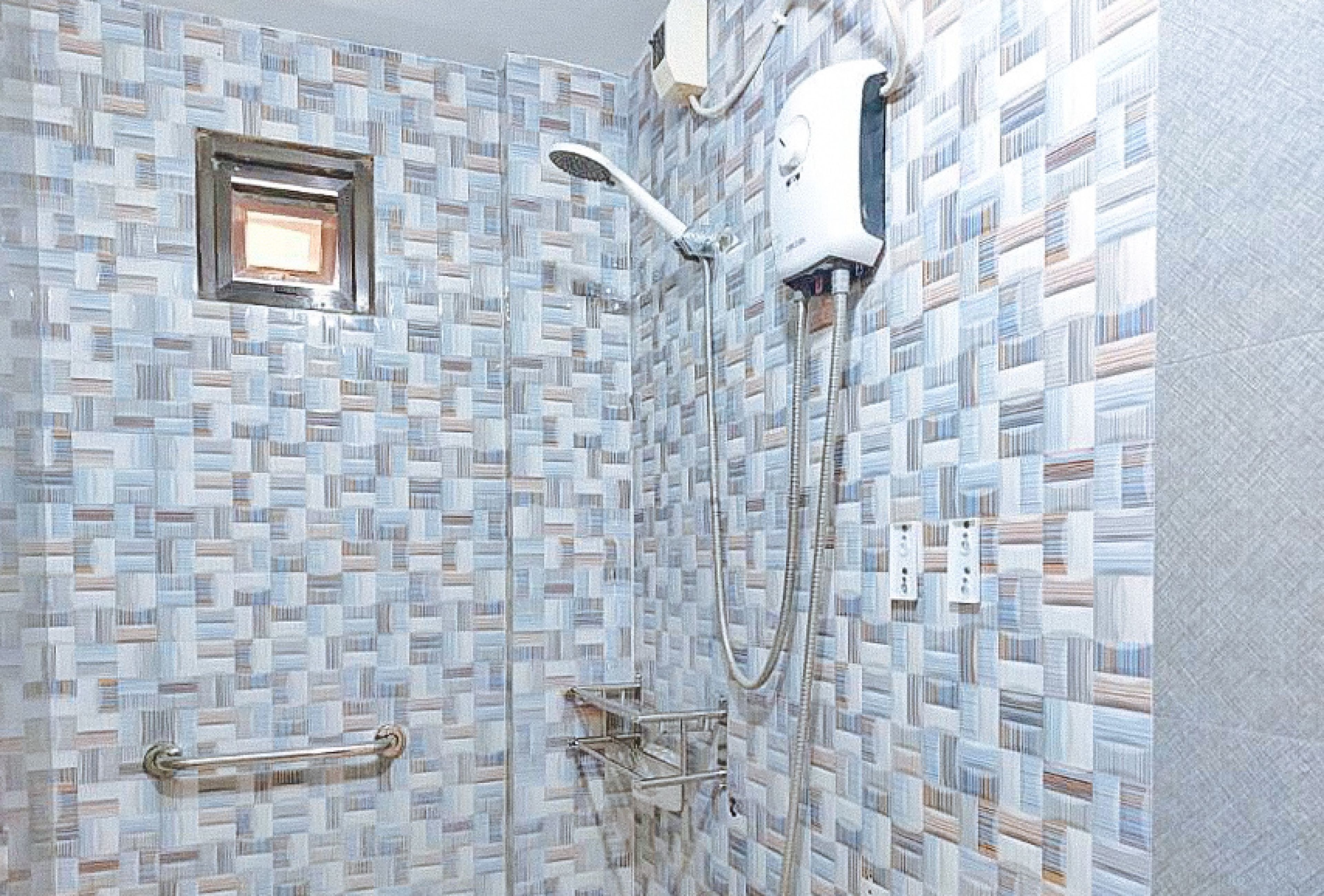A bathroom with a mosaic tile wall, a handheld showerhead, and a wall-mounted faucet.