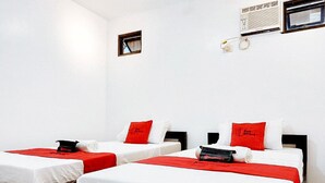 A hotel room with two beds, each with white bedding and red accents. There is a small window and a wall-mounted air conditioning unit. - Reddoorz @ San Antonio Binan Laguna (Biñan City)