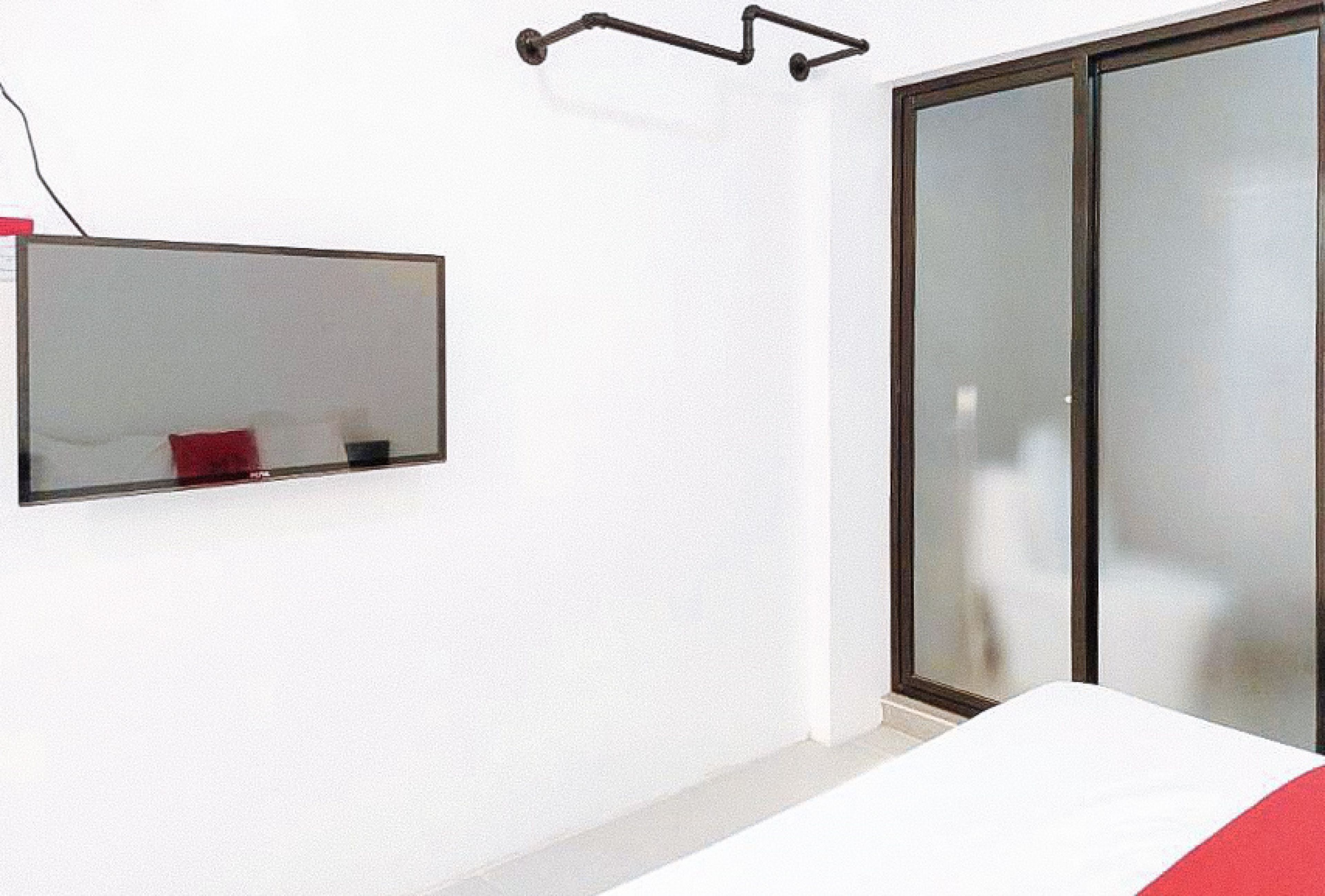 A room with a bed, a mirror, and a sliding glass door.