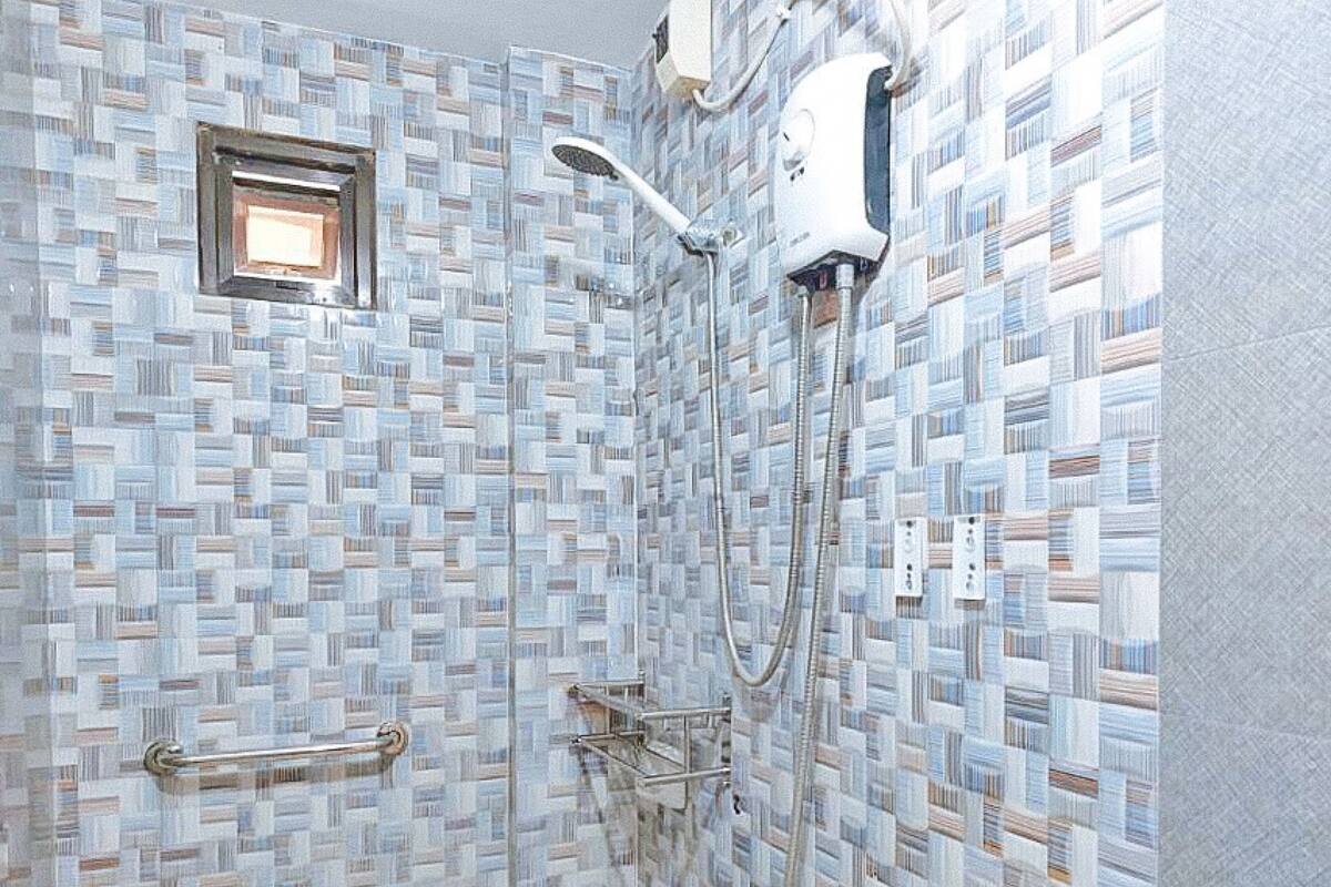A bathroom with a mosaic tile wall, a handheld showerhead, and a wall-mounted faucet.