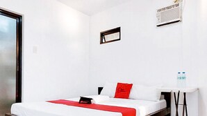 A single bed with a white and red bedspread, a small bedside table, and a water bottle on the wall. - Reddoorz @ San Antonio Binan Laguna (Biñan City)