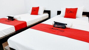A hotel room with three single beds, each with a white mattress and red bedding. - Reddoorz @ San Antonio Binan Laguna (Biñan City)