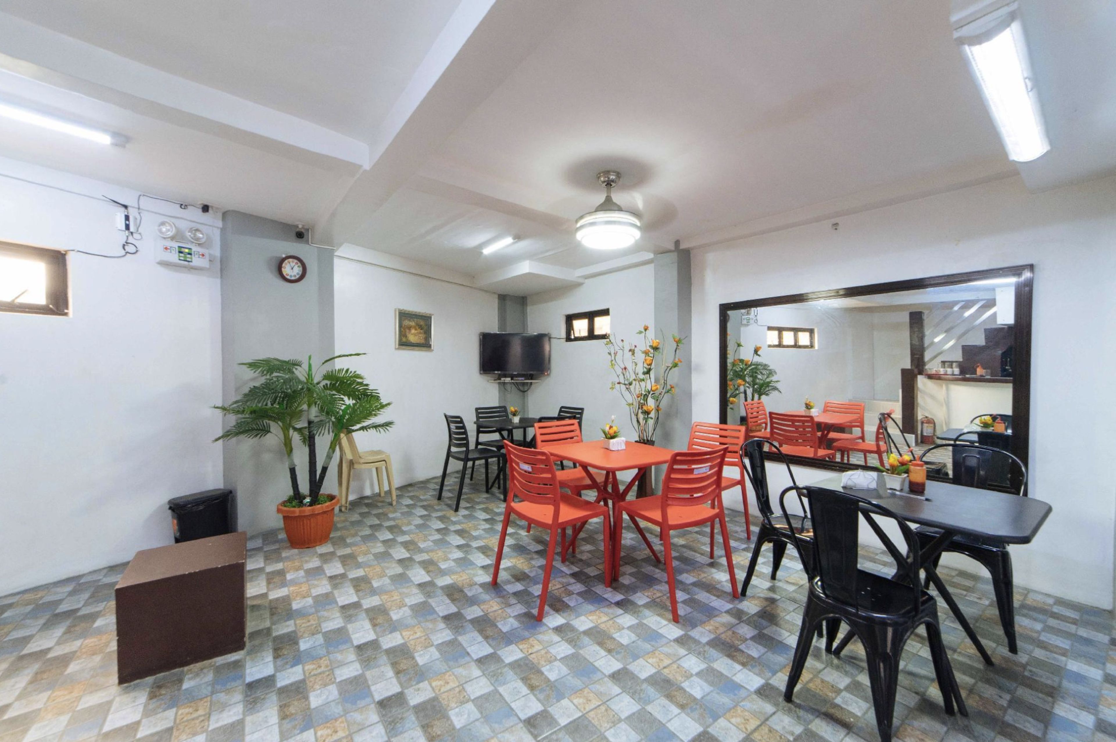 A dining area with a checkered floor, a ceiling fan, and a television mounted on the wall.
