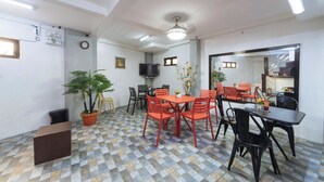 A dining area with a checkered floor, a ceiling fan, and a television mounted on the wall. - Reddoorz @ San Antonio Binan Laguna (Biñan City)