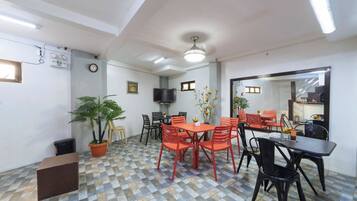 A dining area with a checkered floor, a ceiling fan, and a television mounted on the wall.