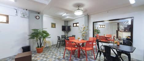 A dining area with a checkered floor, a ceiling fan, and a television mounted on the wall.